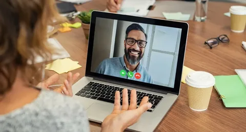 A screenshot of a couple on a video call, both smiling warmly, with soft, cozy room lighting in the background creating an intimate and comforting atmosphere.